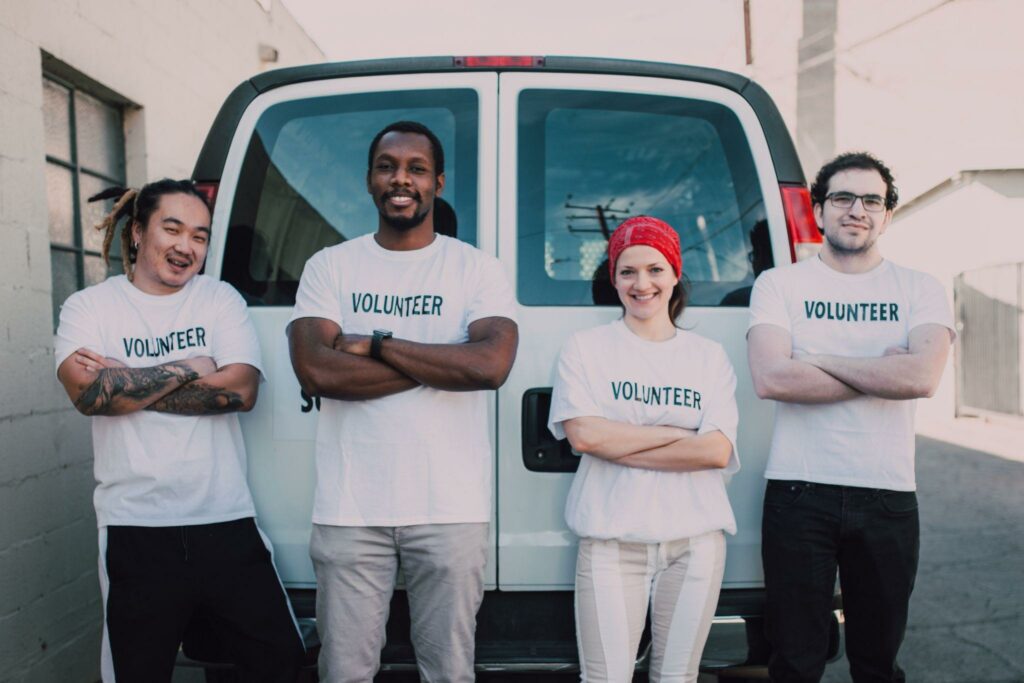 4 volunteers in a nonprofit organization standing in front of white van